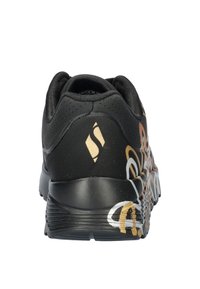 Zapatilla deportiva negra con parte superior texturizada, diseños abstractos coloridos en blanco, naranja y dorado, y una suela de goma para tracción.