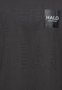 Tissu noir avec de grandes lettres brodées indiquant "OFF DUTY GEAR" et un petit patch noir avec un texte blanc "HALO 196819721981" en haut à droite.