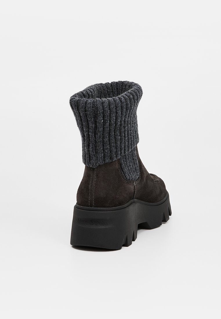 Stivali alla caviglia in suede marrone scuro con un collare a coste in maglia grigia e una robusta suola in gomma nera, dotati di un pannello laterale per una calzata facile.