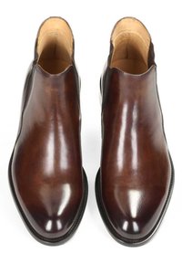 Botine din piele maro, cu o finisare netedă, vârf ascuțit și panouri laterale elastice. Prezintă o talpă contrastantă neagră.