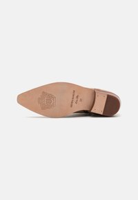 Semelle de chaussure en cuir marron avec une finition texturée. Présente un bout pointu, une semelle intérieure marron clair, un logo embossé et une indication de taille 37.