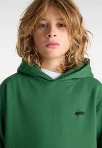 Felpa verde realizzata in tessuto morbido, dotata di tasca a marsupio, cappuccio con cordino e una piccola grafica nera di skateboard sul petto.