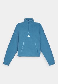 Blå fleecepullover med hög krage, fjärdedelsdragkedja och två sidofickor. Har en texturerad yta och en liten vit logotyp på bröstet.