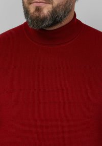 Czerwony prążkowany golf z pionowymi i poziomymi fakturowanymi wzorami, z dopasowanym kołnierzem i średnią grubością.