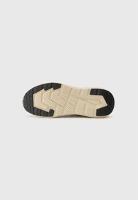 Semelle de sneaker en caoutchouc avec un motif de bande de roulement texturé ; présente un centre beige clair avec des accents noirs et un design angulaire distinct.