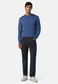 Maglione azzurro lavorato a maglia con scollo rotondo, abbinato a pantaloni scuri e scarpe da ginnastica di colore chiaro. Presenta una vestibilità comoda e un tessuto testurizzato.