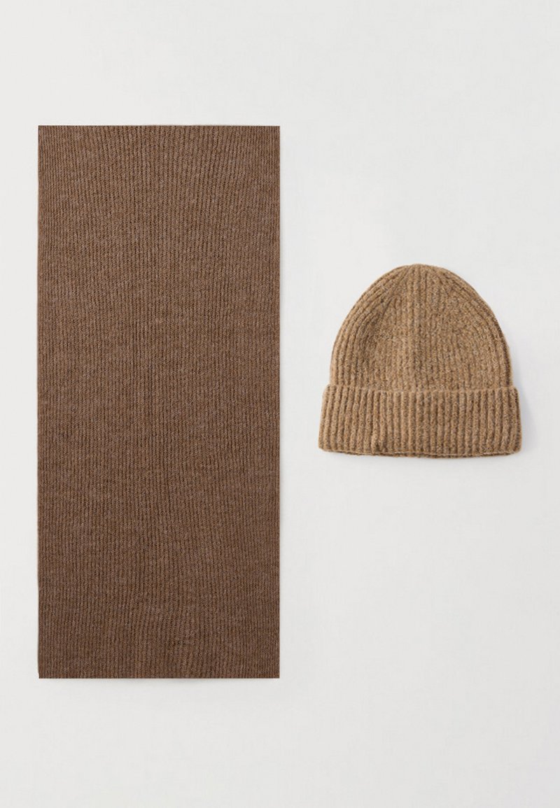 Καφέ ριπ πλεκτό κασκόλ και ανοιχτό καφέ πλεκτό σκουφάκι, και τα δύο κατασκευασμένα από μαλακό ύφασμα. Το κασκόλ είναι ορθογώνιο, ενώ το σκουφάκι έχει στρογγυλεμένη κορυφή.