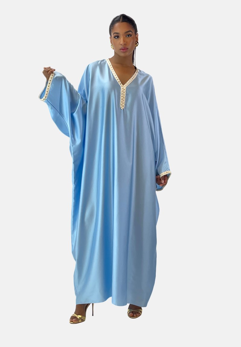 Kaftano azzurro chiaro realizzato in tessuto simile alla satin, con scollatura a V rifinita con bordo decorativo in avorio e maniche ampie. Accenti dorati sulle calzature.