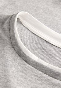 Gray cotton fabric with a ribbed texture and a white, smooth crew neck. Close-up view highlighting stitching details and fabric weave.