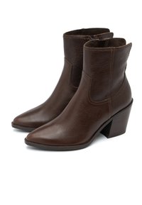 Botine din piele maro, cu vârf ascuțit, panouri elastice laterale și toc masiv. Au o textură netedă și detalii minime de coasere.