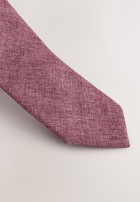 Burgundy tie made of textured fabric, featuring a narrow width and a pointed end, with subtle variations in color throughout.