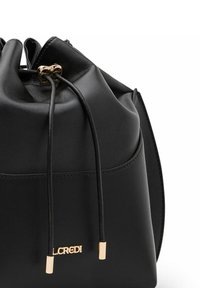Sac seau en cuir noir avec fermeture à cordon, accents en métal doré, et plaque de logo. Texture lisse et forme structurée.
