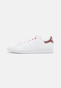 Vita lädersneakers med rundad tå, tre perforerade ränder och kontrasterande orange och röda detaljer på hälen och snörhålen.