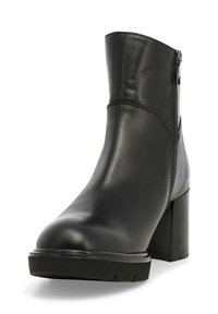 Stivale alla caviglia in pelle nera con punta rotonda, cerniera laterale e tacco alto chunky; texture liscia e dettagli di cucitura sottili.
