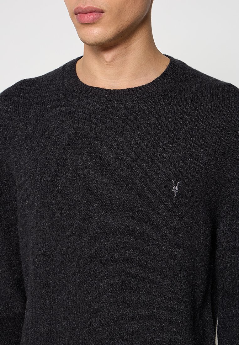 Schwarzer Strickpullover mit Rundhalsausschnitt, mit einer weichen Textur und einem kleinen, gestickten Logo auf der linken Brust.