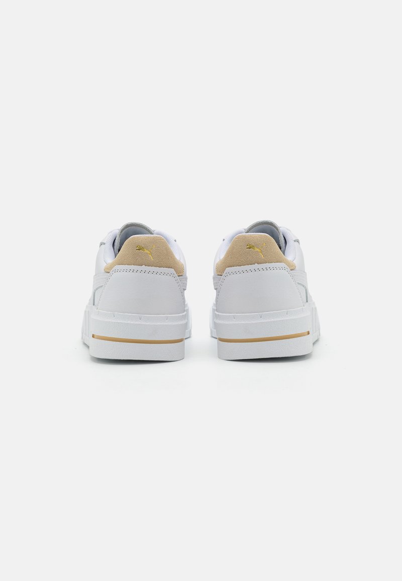 Baskets blanches en cuir avec un accent de talon beige texturé, une doublure intérieure grise et un détail de logo doré à l'arrière. Semelle en caoutchouc plate.