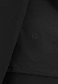 Czarny sportowy top z żeberkowym wzorem, krótkimi rękawami i subtelnym wyszytym logo. Gładki materiał o czystym, minimalistycznym designie.