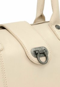 Primo piano di una borsa in pelle beige con fibbia in metallo argentato e manici cuciti.