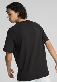 Sort kortærmet t-shirt med rund hals, der har en glat tekstur og en afslappet pasform. Bagsiden viser et simpelt, udekoreret design.