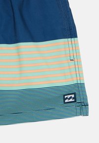 Pantaloni da surf con righe orizzontali in blu navy, azzurro e pesca. Include un piccolo logo con un design a onda.