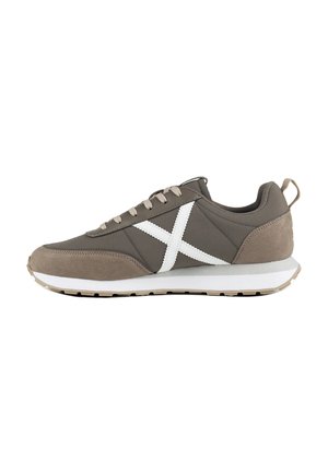 Zapatilla gris de corte bajo con puntera y talón de ante beige, suela blanca, cordones beige y una gran X blanca bordada en el lateral.