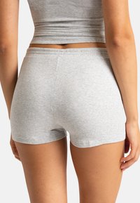 Shorts gris à côtes avec une taille élastique, présentant une texture lisse et une coupe ajustée. Le design est simple et minimaliste.