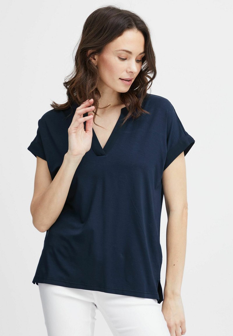 Top blu navy a maniche corte con scollatura a V e risvolti, caratterizzato da una vestibilità rilassata e spacchi laterali all'orlo, realizzato in un materiale morbido.