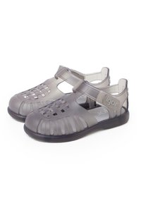 Sandali in PVC grigi con design a intreccio aperto, cinturini regolabili e suola in gomma nera. Leggeri, flessibili e resistenti all'acqua.