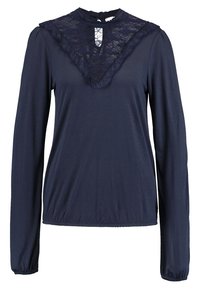 Marinblå långärmad topp med en spetsbesatt ståkrage, samlade ärmslut och en subtil volang längs halsringningen. Slät tygtextur.