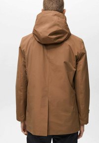 Brun vandtæt jakke med hætte, der har en lige snit, rygventilation og lange ærmer. Glat tekstur og minimalistisk design.