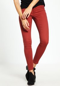 Czerwone, dopasowane dżinsy z denimu, o gładkiej teksturze i slim fit, zestawione z czarnymi botkami za kostkę.