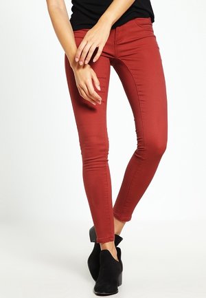 Røde, tætsiddende jeans lavet af denim, med en glat tekstur og slank design, parret med sorte ankelstøvler.