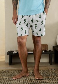 Grå shorts med et kaktusmønster i grøn, lavet af et blødt stof. Designet har elastisk talje og sidelommer.