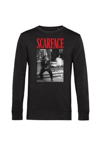 Maglietta nera a maniche lunghe con il testo rosso "SCARFACE" sopra una scena in bianco e nero di un uomo che spara in un ambiente chiuso con fumi circostanti.