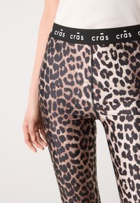 Panterprint leggings met een gladde textuur, een zwarte elastische tailleband met de merknaam en een aansluitend ontwerp.