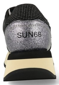 Sneaker nera con tacco in glitter argentato, tomaia in mesh, colletto imbottito e suola in gomma a righe. Presenta il logo "SUN68" sul tallone.