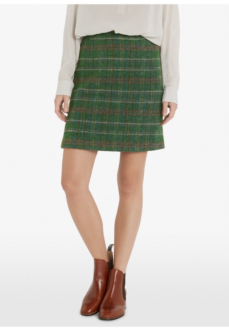 Vihreä ruudullinen hame, joka on valmistettu tekstuurillisesta kankaasta ruskeilla yksityiskohdilla. A-linjainen, mid-thigh-pituinen, yhdistetty ruskeisiin nilkkureihin.