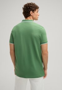 Grüne Poloshirt aus Baumwollstoff mit klassischem Kragen. Verfügt über weiße Besätze an den Ärmeln und einen geraden Schnitt. Rückansicht, keine sichtbaren Grafiken.