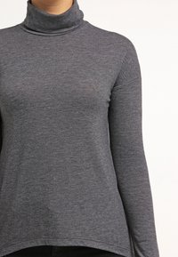Maglione grigio a collo alto realizzato in tessuto morbido e elasticizzato, con maniche lunghe e orlo curvo per un fit rilassato.