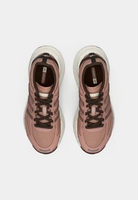 Lyserosa joggesko med mesh-overdel, brune snørebånd og hvit såle. Har et strukturert design og logo på tungen.