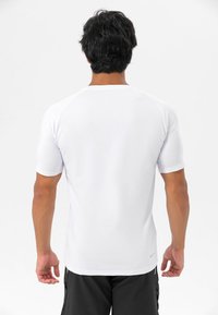 Hvit, kortermet treningstrøye med en glatt tekstur og en tettsittende design, med raglanermer og rund hals.