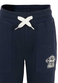 Marineblauwe sweatpants met geribbelde tailleband, witte trekkoord in een strik, en Timberland-logo op de linker bovenbeenzak.