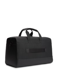 Μαύρη τσάντα τύπου ντουφέκ με υφή από συνθετικό υλικό, με διπλές χειρολαβές στην κορυφή και λείο κάτω πάνελ. Μινιμαλιστικός σχεδιασμός, ορθογώνιο σχήμα.