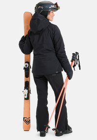 Skiing attire includes a black insulated jacket with a hood, black pants, orange ski poles, and orange skis with black bindings.