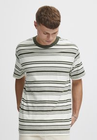 Kortermet T-skjorte i off-white med mørkegrønne horisontale striper, rund hals, myk tekstur, avslappet passform og sideåpning.
