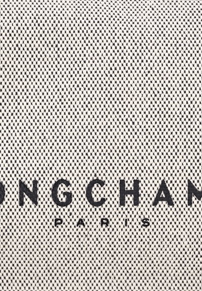 Gewebter Stoff in Creme mit schwarzem Text, der "LONGCHAMP" und "PARIS" liest, mit einem strukturierten Muster und einem robusten, stabilen Erscheinungsbild.