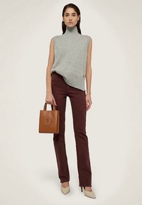 Jersey gris sin mangas con cuello alto, pantalones burdeos, tacones beige y un bolso tote de cuero marrón, con un relieve de logotipo y un diseño estructurado.