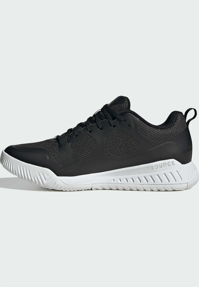 Chaussures de sport noires avec un dessus texturé, une semelle intermédiaire blanche et des crampons prononcés. Les caractéristiques incluent un col rembourré et un système de laçage.