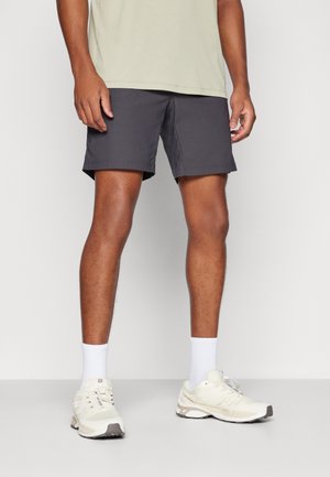 Gray shorts with a relaxed fit, paired with white crew socks and light-colored running shoes. The shirt is a light beige or cream color.