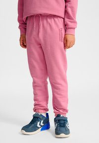 Pantalones deportivos rosas con cintura elástica y cordón, con un acabado texturizado. Combinados con zapatillas azules con detalles blancos.